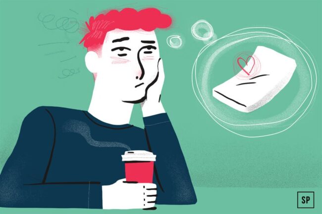 Eine müde Person mit rosafarbenem Haar hält eine Kaffeetasse und stützt ihr Gesicht auf eine Hand, während sie von einem kuscheligen Kissen mit einem Herz darauf träumt - sie spürt deutlich die Auswirkungen des Schlafentzugs. Der Hintergrund ist grün.