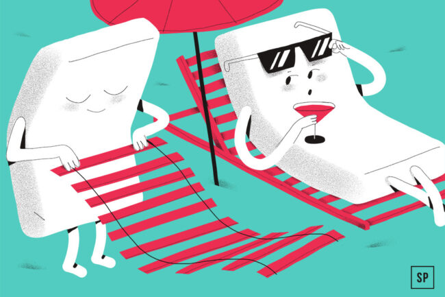 Zwei Cartoon-Marshmallows am Strand: Der eine liegt in einem roten Liegestuhl - bequemer als jeder Lattenrost -, trägt eine Sonnenbrille und nippt an einem Cocktail, während der andere einen Stuhl unter einem roten Sonnenschirm webt oder repariert.