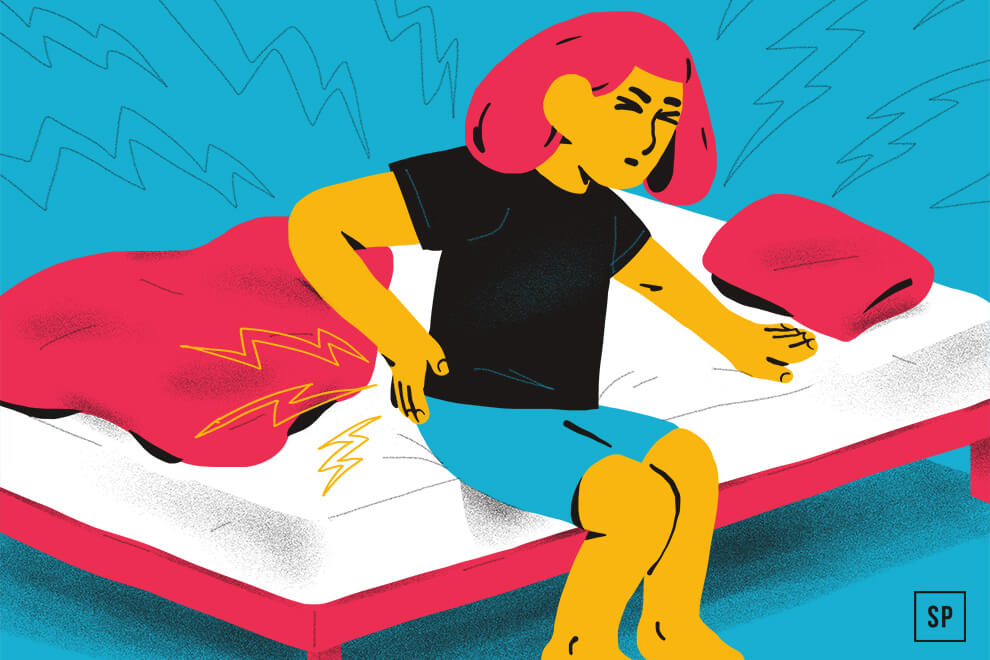 Eine illustrierte Person mit rosafarbenem Haar sitzt auf einem Bett und hält sich vor Schmerzen den unteren Rücken - Rückenschmerzen nach dem Aufstehen -, während rote und gelbe Blitze ihr Unbehagen unterstreichen. Das zerknitterte Bettlaken und der blaue Hintergrund vervollständigen die Szene.