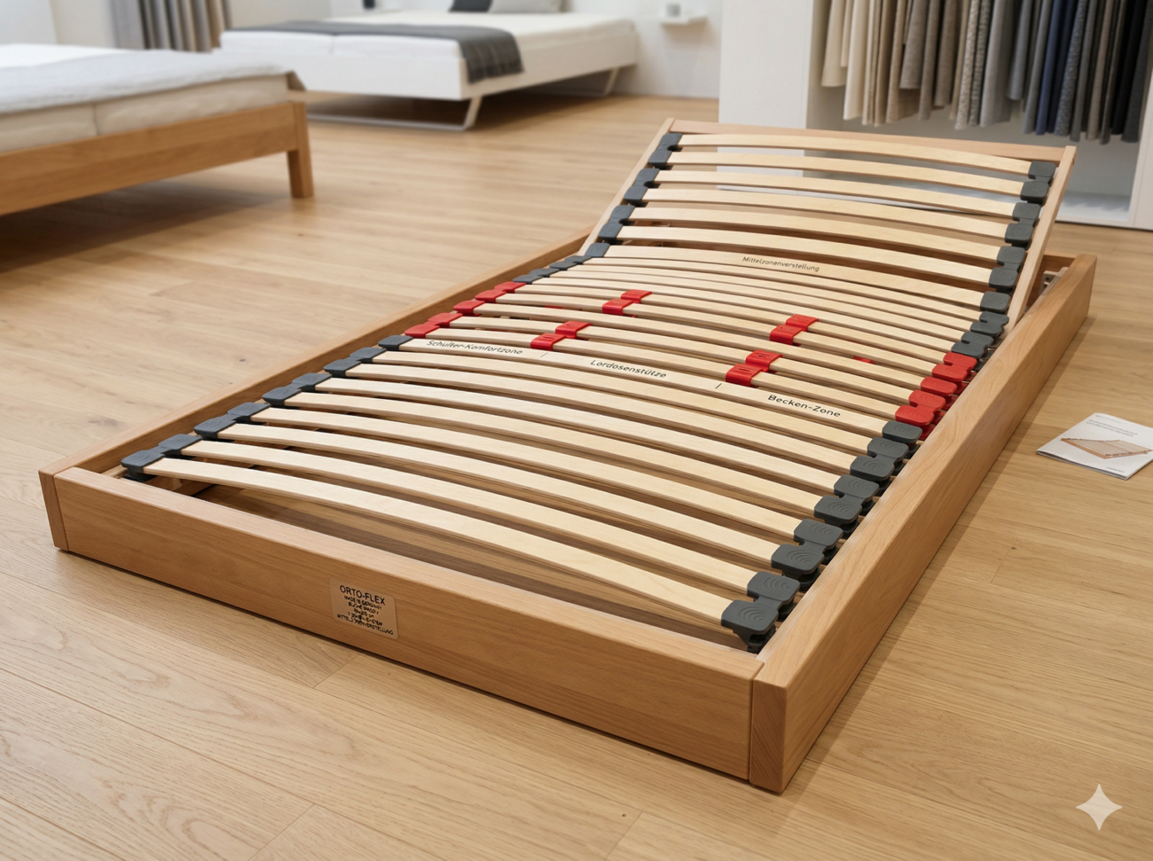 Orto-Flex-Holzlattenrost mit beschrifteten ergonomischen Zonen, einschließlich Schulter-, Lenden- und Beckenstützbereichen, die mit roten und grauen Verbindungsstücken markiert sind, ausgestellt in einem Ausstellungsraum.