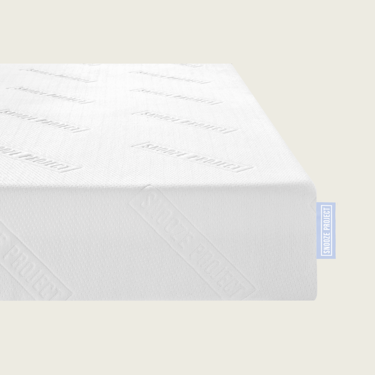 matratze-allgemein Eine Nahaufnahme der weißen Familienbett Matratze mit der Prägung "SNOOZE PROJECT" auf der Oberfläche und einem blauen SNOOZE PROJECT Stoffanhänger an der Seite. Die Matratze ist ideal für Ihr Familienbett und steht vor einem unifarbenen, hellbeigen Hintergrund.
