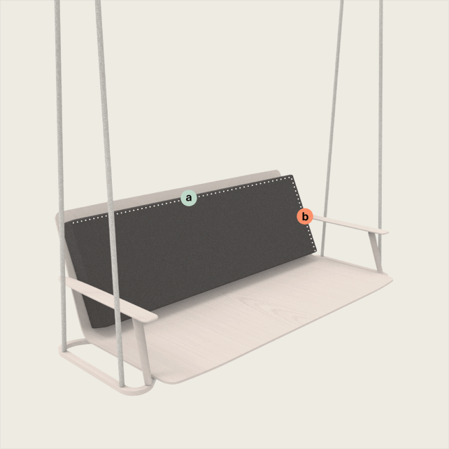 Eine minimalistische Schaukel mit einem hellen Holzsitz und Armlehnen, die an Seilen aufgehängt sind. An der Rückenlehne liegt ein dunkles, rechteckiges Kissen mit der Aufschrift a. Auf der rechten Seite des Kissens befindet sich ein kleines b.