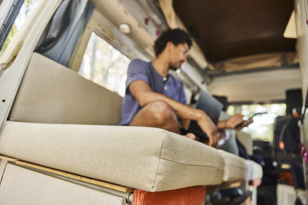 Ein Mann sitzt auf Polstern in seinem Bus.