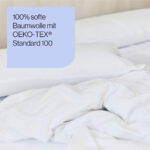 Eine Nahaufnahme eines ungemachten Bettes mit weißen Laken und Kissen. Der überlagerte Text lautet: 100% weiche Baumwolle mit OEKO-TEX® Standard 100 auf hellblauem Hintergrund.