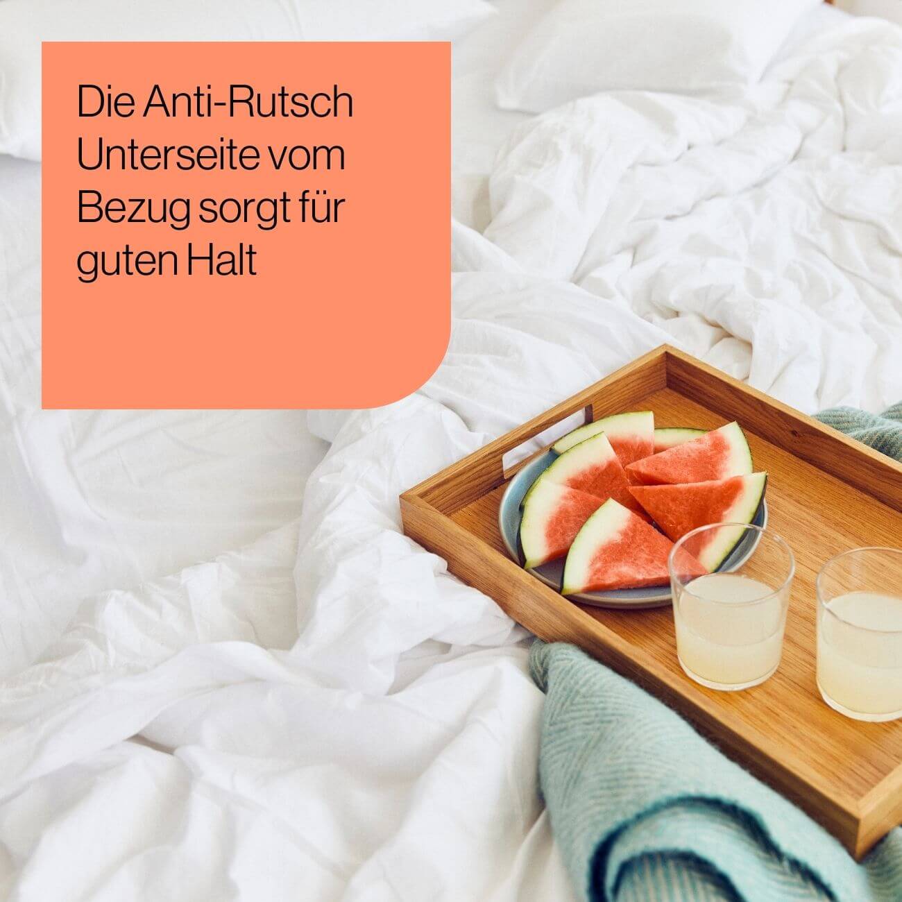 20 Ein Holztablett mit Wassermelonenstücken und zwei Gläsern Saft steht auf einem Bett mit weißer Bettwäsche. Links oben steht: Die Anti-Rutsch Unterseite vom Bezug sorgt für guten Halt.