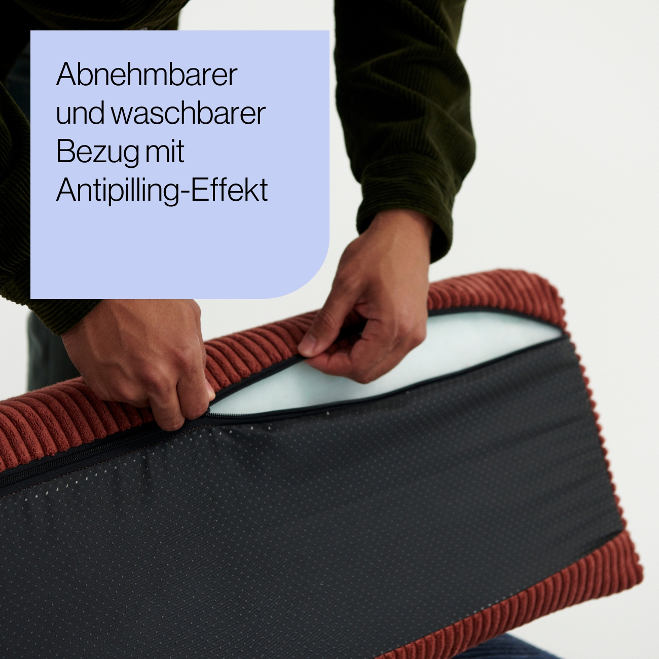 Levi_Produkt-Mood_02 Eine Person öffnet den Reißverschluss eines strukturierten Kissenbezugs und enthüllt das innere Kissen. Der Text auf Deutsch lautet: Abnehmbarer und waschbarer Bezug mit Antipilling-Effekt (Abnehmbarer und waschbarer Bezug mit Antipilling-Effekt).