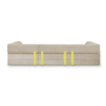 Ein modernes beigefarbenes 3-Sitzer-Sofa mit klaren Linien, von der Rückseite aus gesehen, verfügt über vier vertikale gelbe Bänder, die gleichmäßig über die Rückseite verteilt sind, um einen stilvollen modularen Sofa-Look zu erzielen.