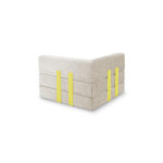 Eine moderne, L-förmige Levi-Polsterbank in Beige mit drei horizontalen Sitzschichten und vier vertikalen gelben Akzentriemen. Das minimalistische Design des modularen Sessels wird auf einem weißen Hintergrund präsentiert.
