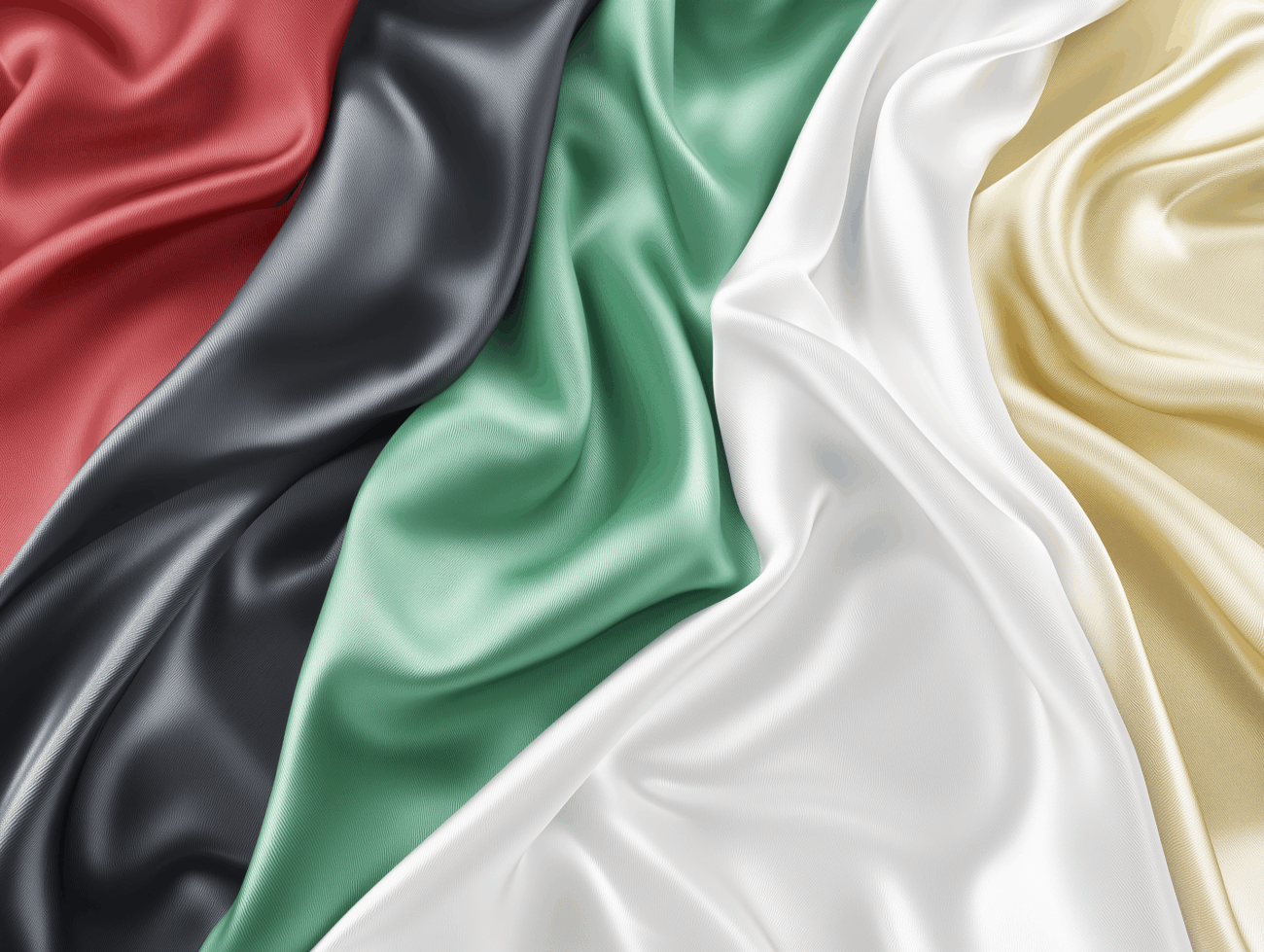 Nahaufnahme eines fließenden Acetat-Stoffes mit fünf verschiedenen Farben: rot, schwarz, grün, weiß und gelb, angeordnet in diagonalen Streifen. Die seidenartige Textur erzeugt weiche Falten und Highlights.