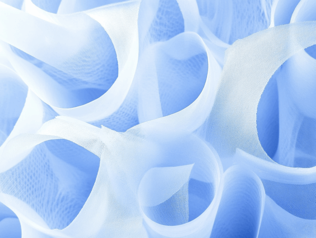 Nahaufnahme eines hellblauen, durchsichtigen Polypropylengewebes mit weichen Falten und Kurven, die ein abstraktes, luftiges Muster und eine Textur erzeugen.