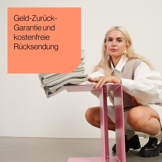 Eine Frau mit langen blonden Haaren hockt neben einem rosa Tisch und hält einen Stapel Zeitschriften in der Hand. Der Text in einem korallenroten Kasten lautet: "Geld-Zurück-Garantie und kostenfreie Rücksendung".