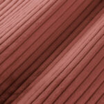 Nahaufnahme eines weichen, gerippten Stoffes in einem staubigen Rosa, der parallele, erhabene Rillen und eine samtige Textur aufweist.