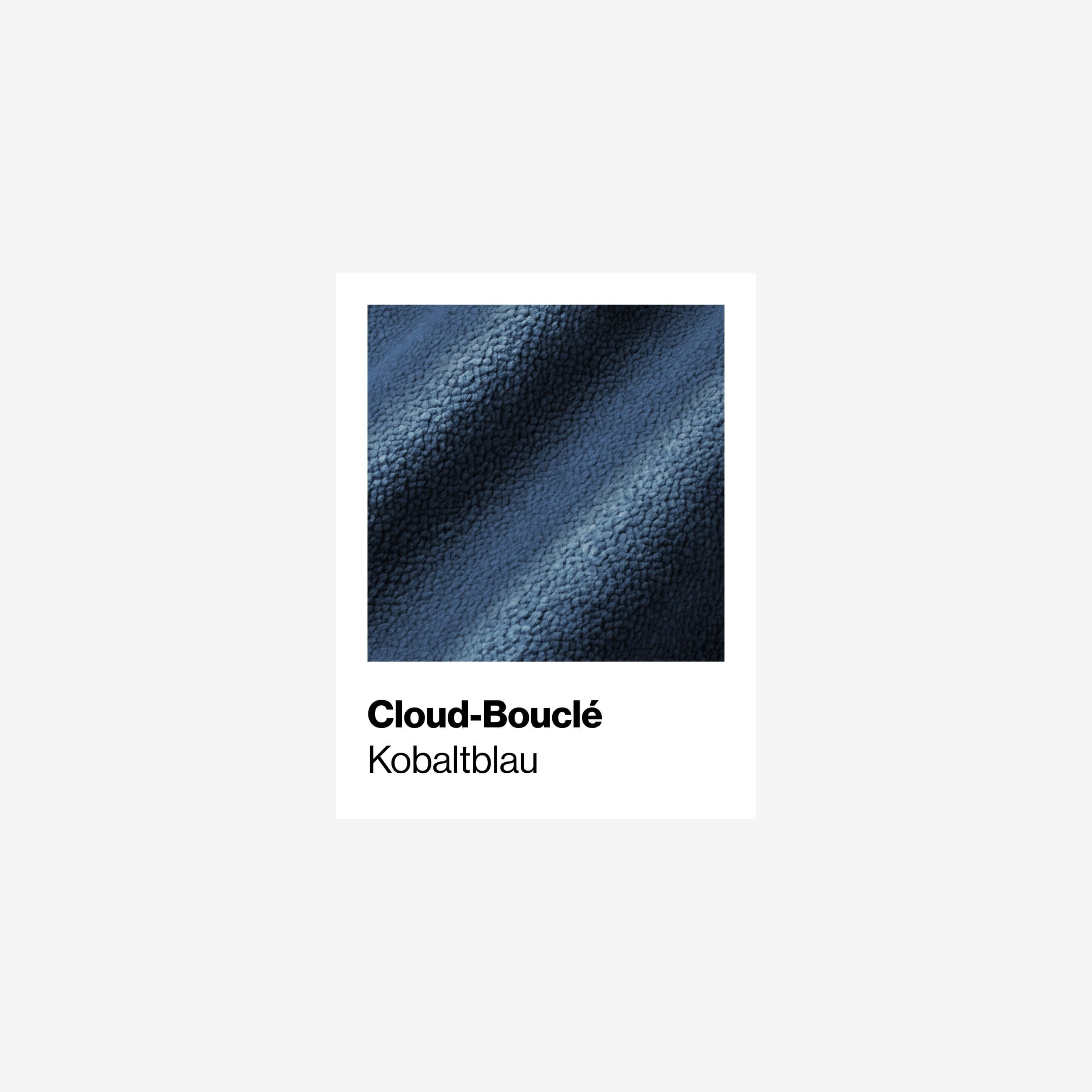 Nahaufnahme eines strukturierten Stoffes mit der Bezeichnung Cloud-Bouclé in Kobaltblau, der eine weiche, leicht holprige Oberfläche mit wellenförmigen Schatten aufweist. Der Hintergrund ist weiß mit Text unter dem Stoffmuster.