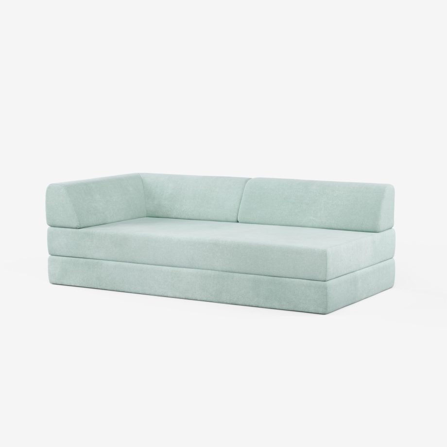 Ein modernes, hellblau gepolstertes Sofa mit niedriger Rückenlehne und Armlehne auf der linken Seite, vor einem schlichten weißen Hintergrund.
