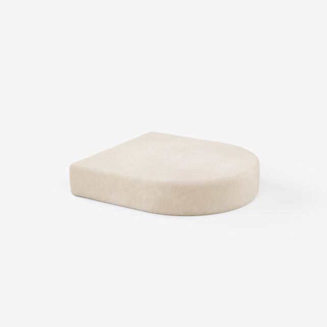 Ein beigefarbenes, halbkreisförmiges Kissen mit flacher Basis und abgerundetem Rand auf weißem Hintergrund.
