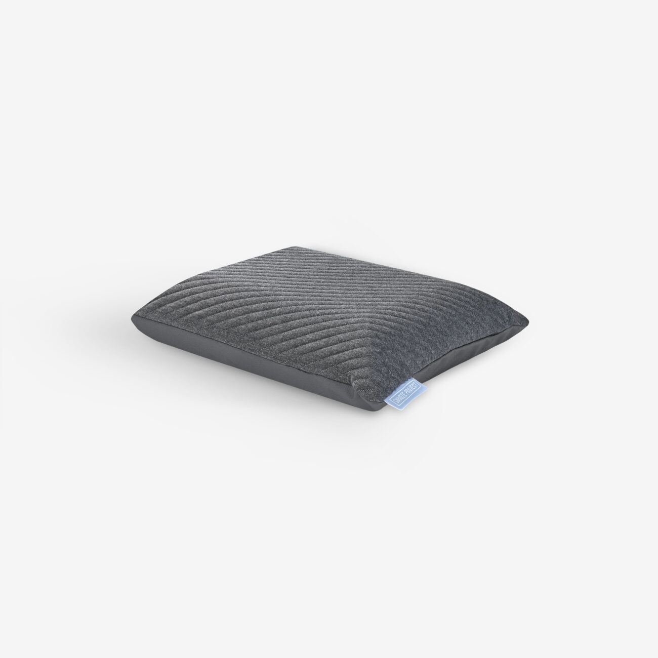 SPKOD45x30_img001-20260223 Ein graues, quadratisches Kissen mit einer strukturierten, gerippten Oberfläche und einem kleinen blauen Anhänger auf einer Seite auf weißem Hintergrund.