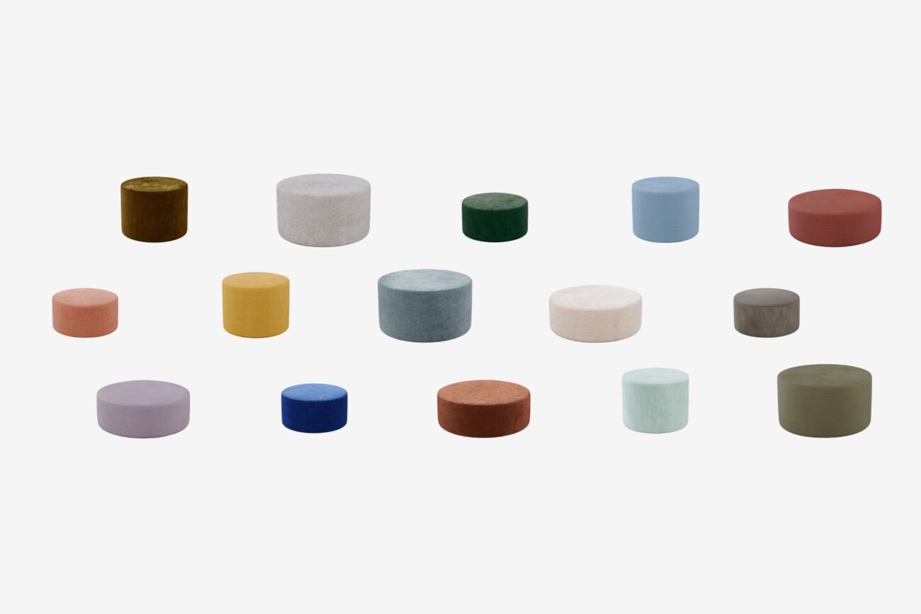 Sechzehn runde Ottomane in verschiedenen Größen und Farben, darunter Grün-, Blau-, Braun-, Violett-, Gelb-, Orange-, Rot-, Beige- und Grautöne, sind in Reihen auf einem schlichten weißen Hintergrund angeordnet.