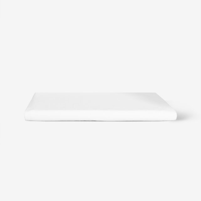 Ein fein säuberlich gefaltetes weißes Bettlaken liegt auf einer schlichten weißen Fläche mit minimalistischem Hintergrund.