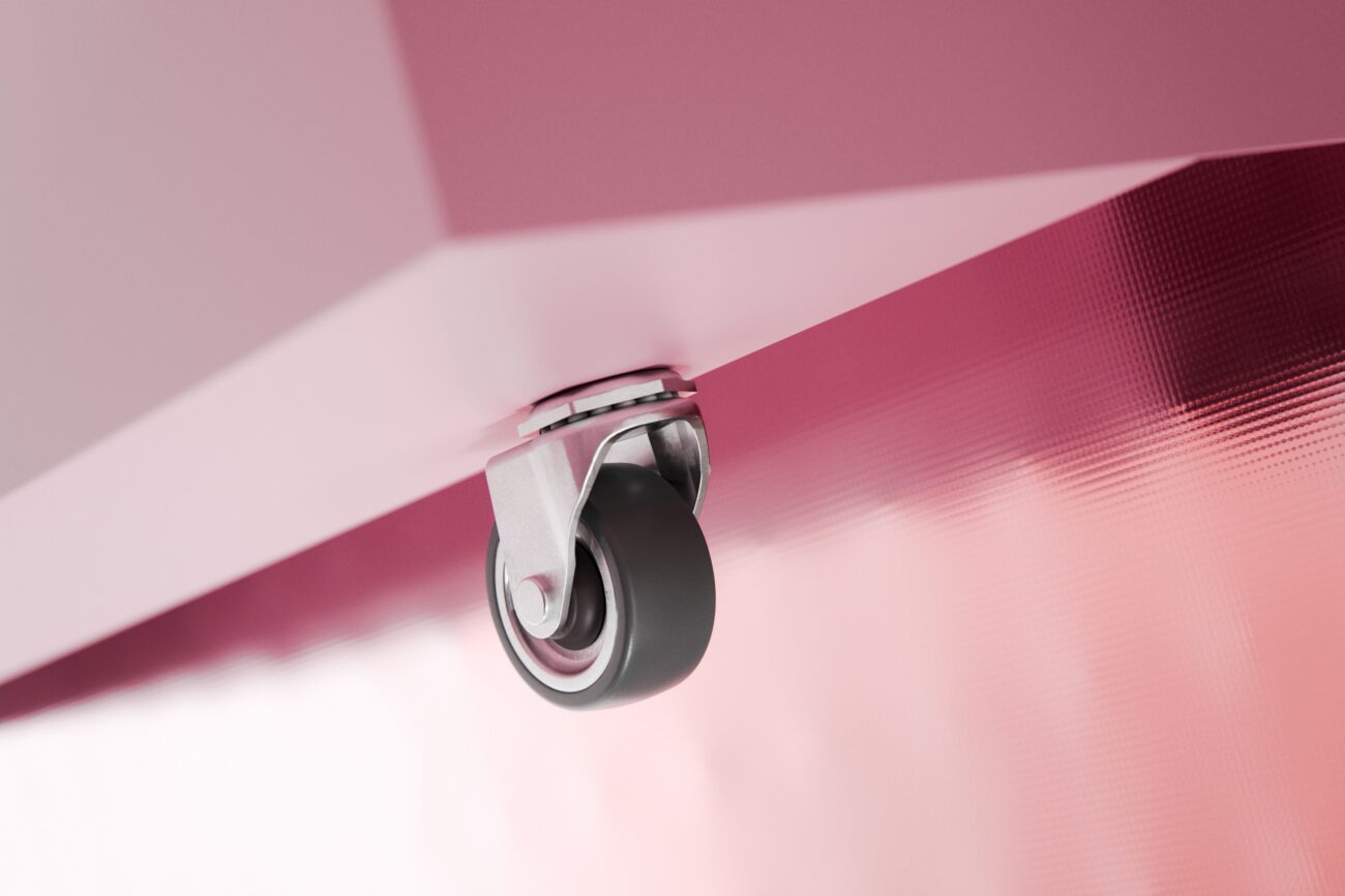 Nahaufnahme eines einzelnen Lenkrollens, das an der Unterseite einer rosa, strukturierten Metalloberfläche befestigt ist, mit sanfter Beleuchtung und unscharfem Hintergrund.