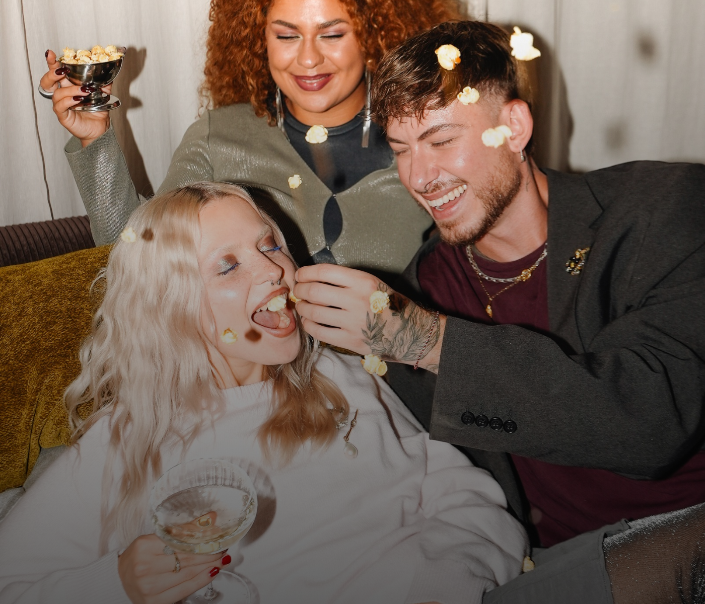 Drei Freunde, die gemeinsam Popcorn essen und dabei lachen.
